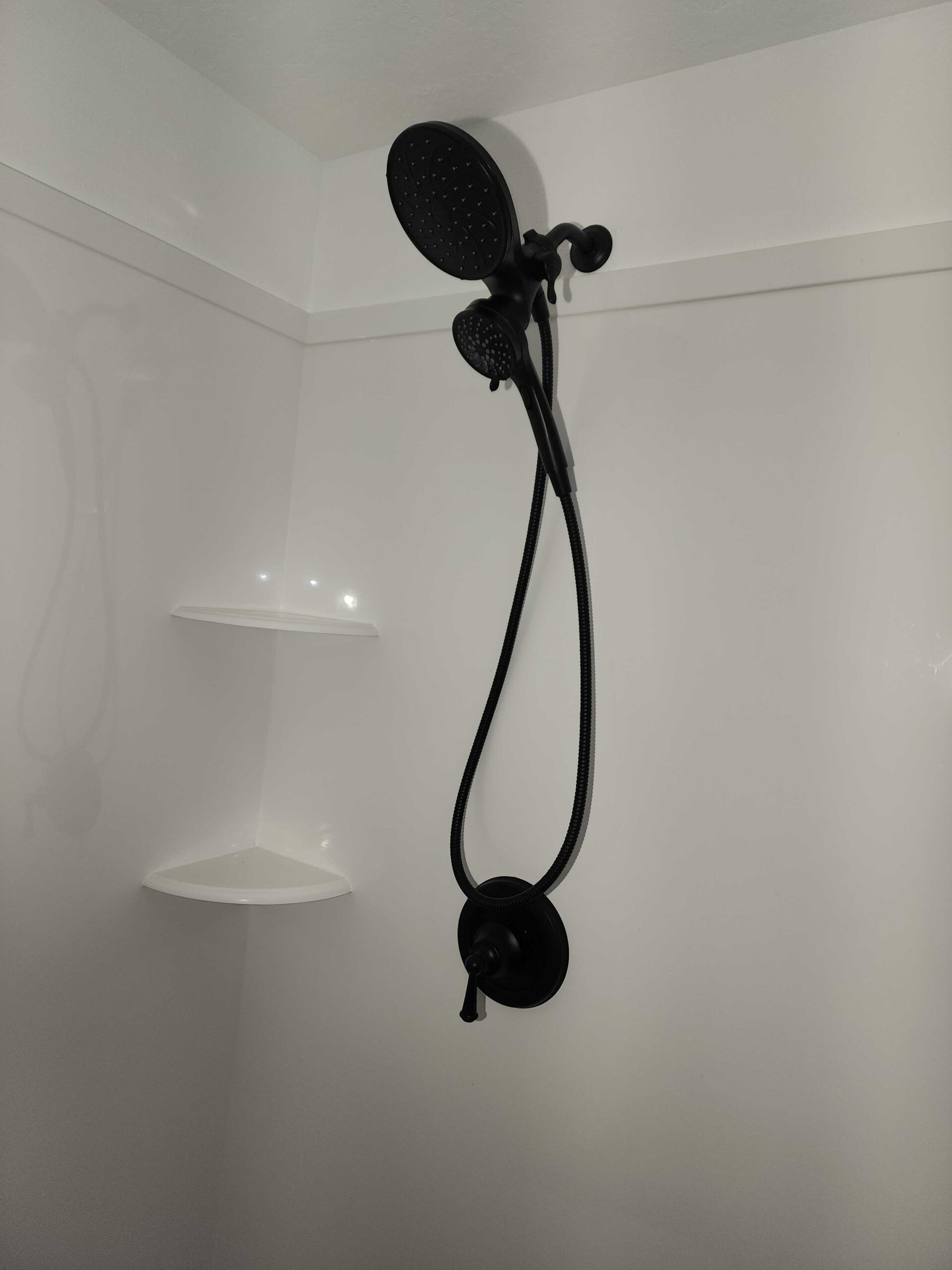 Newly installed handheld showerhead in white shower surround