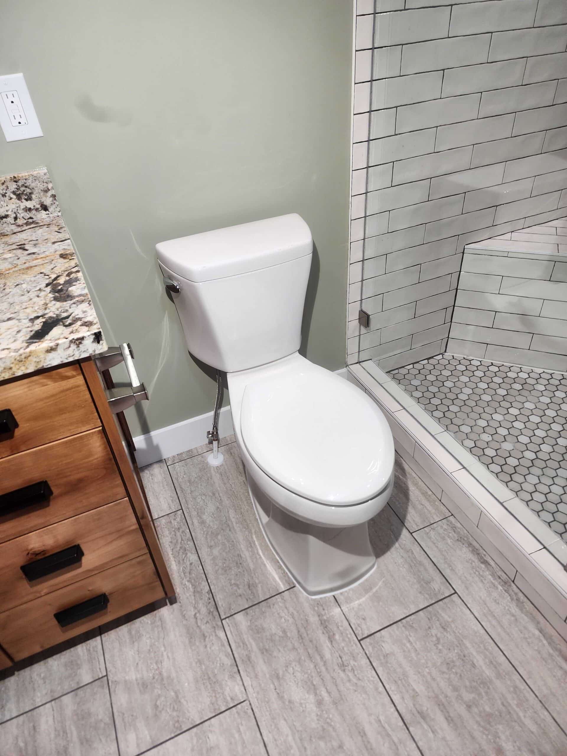 Newly installed toilet next to tiled shower enclosure